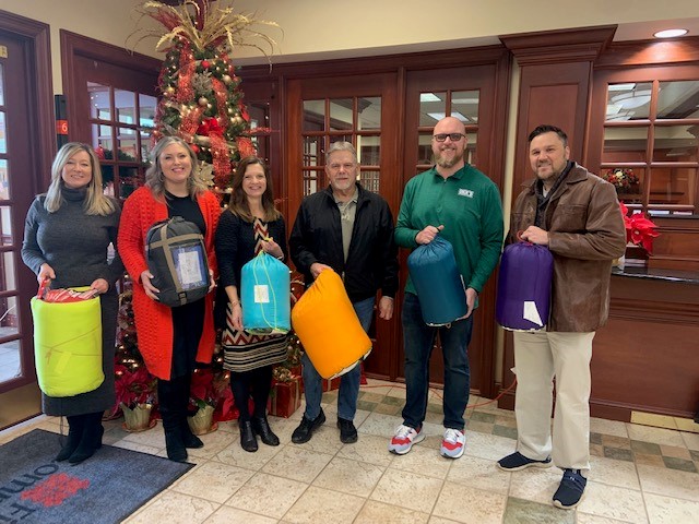 First Community Bank employees holding sleeping bags to be donated. 