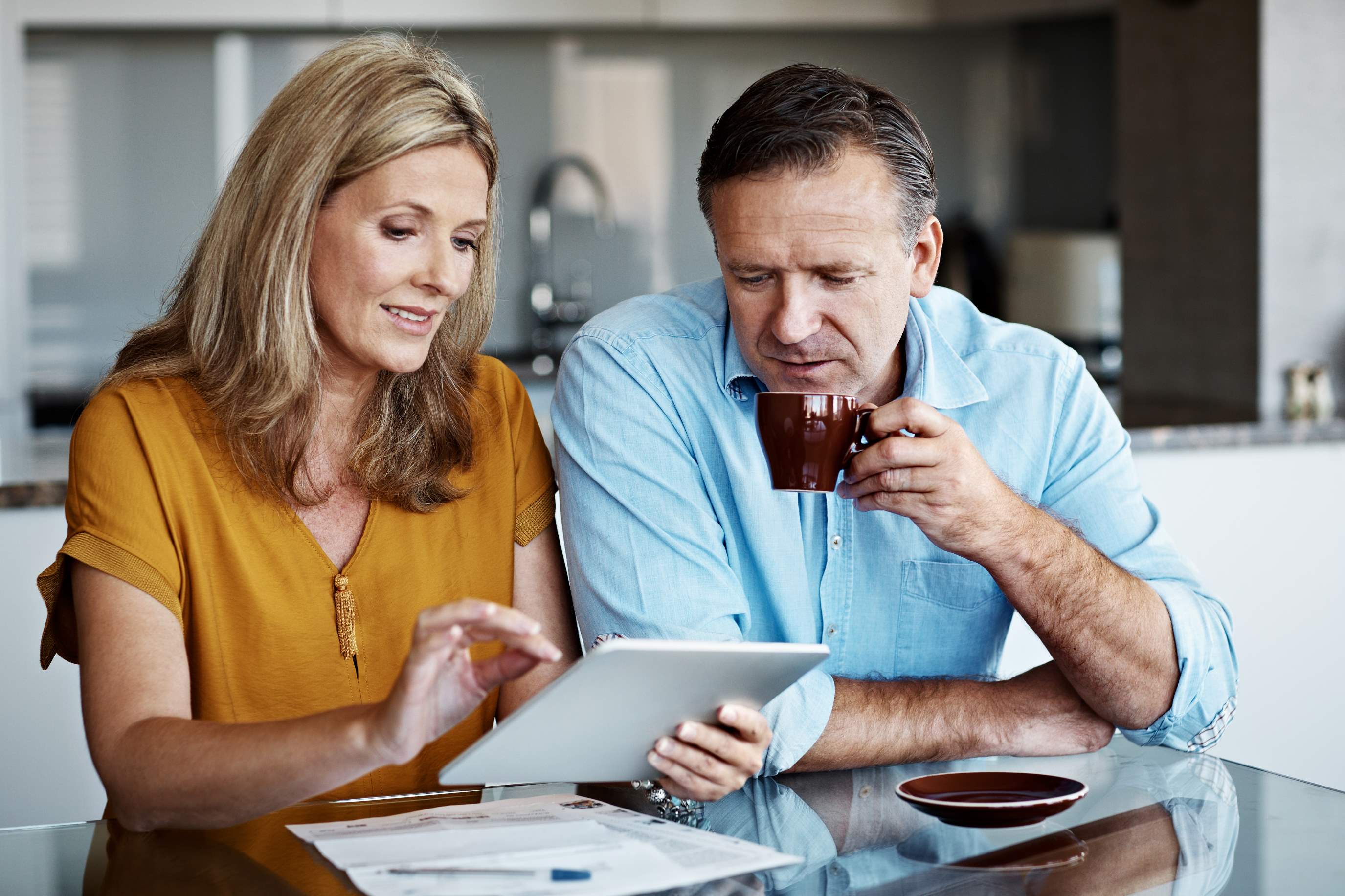 Couple sitting at a table on a tablet.